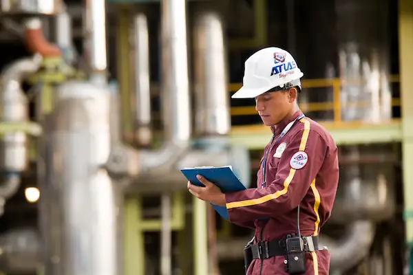 Guarda de seguridad Atlas con casco revisando reporte en complejo industrial en Colombia